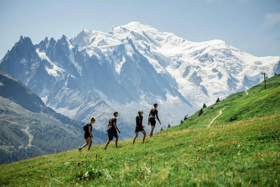 Grupo de trekkers en praderas alpinas con el Mont Blanc al fondo