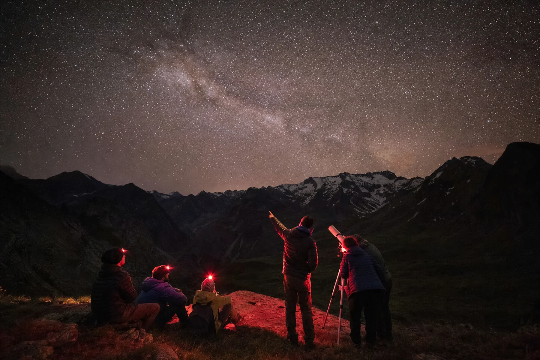 Grupo observando el cielo nocturno estrellado en la montaña