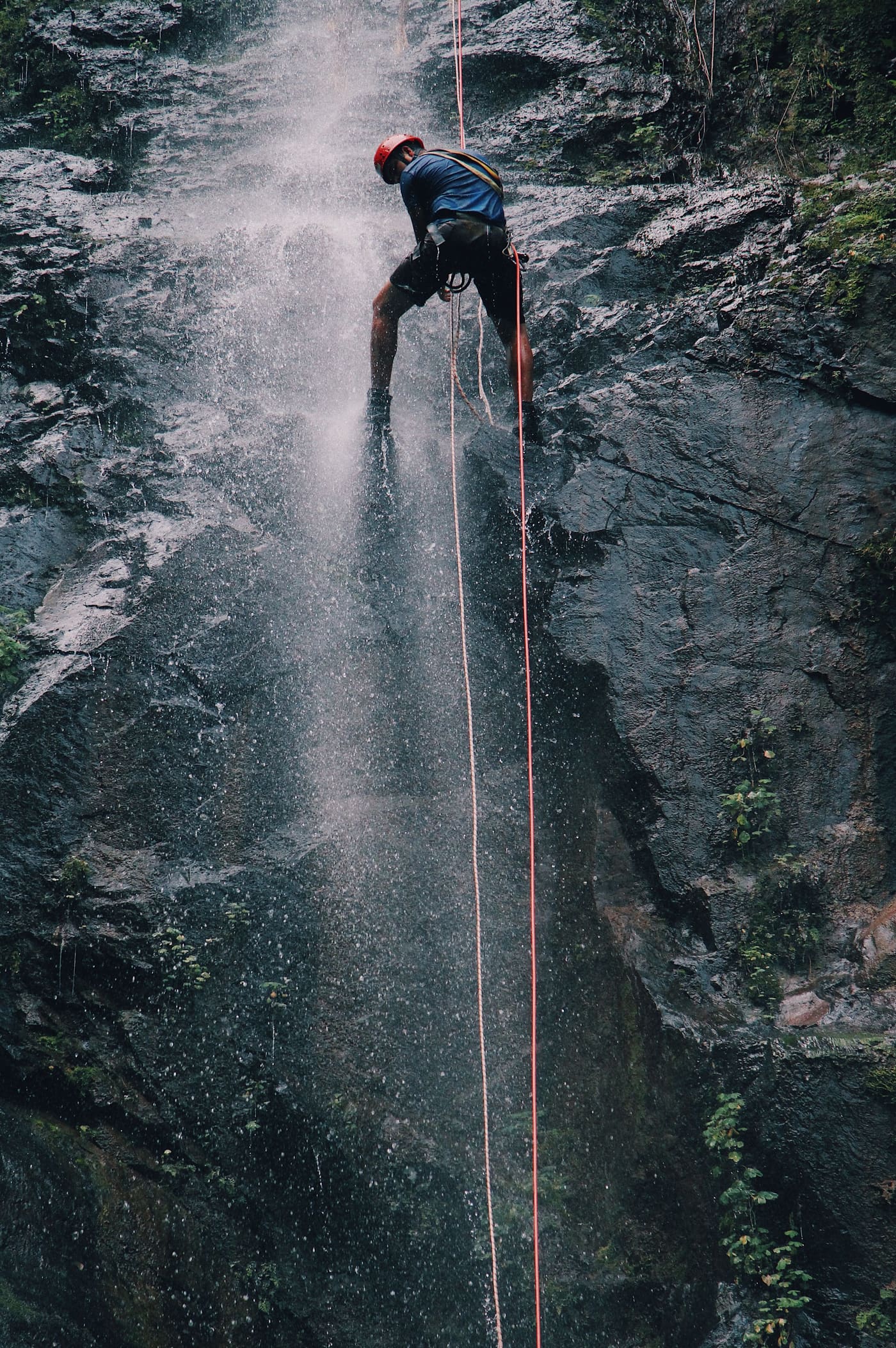 Persona en rápel descendiendo una gran cascada en un barranco técnico