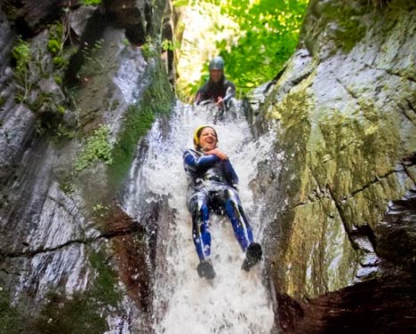 Persona deslizándose por un tobogán natural de agua en el barranco de Bausen, Val d'Aran