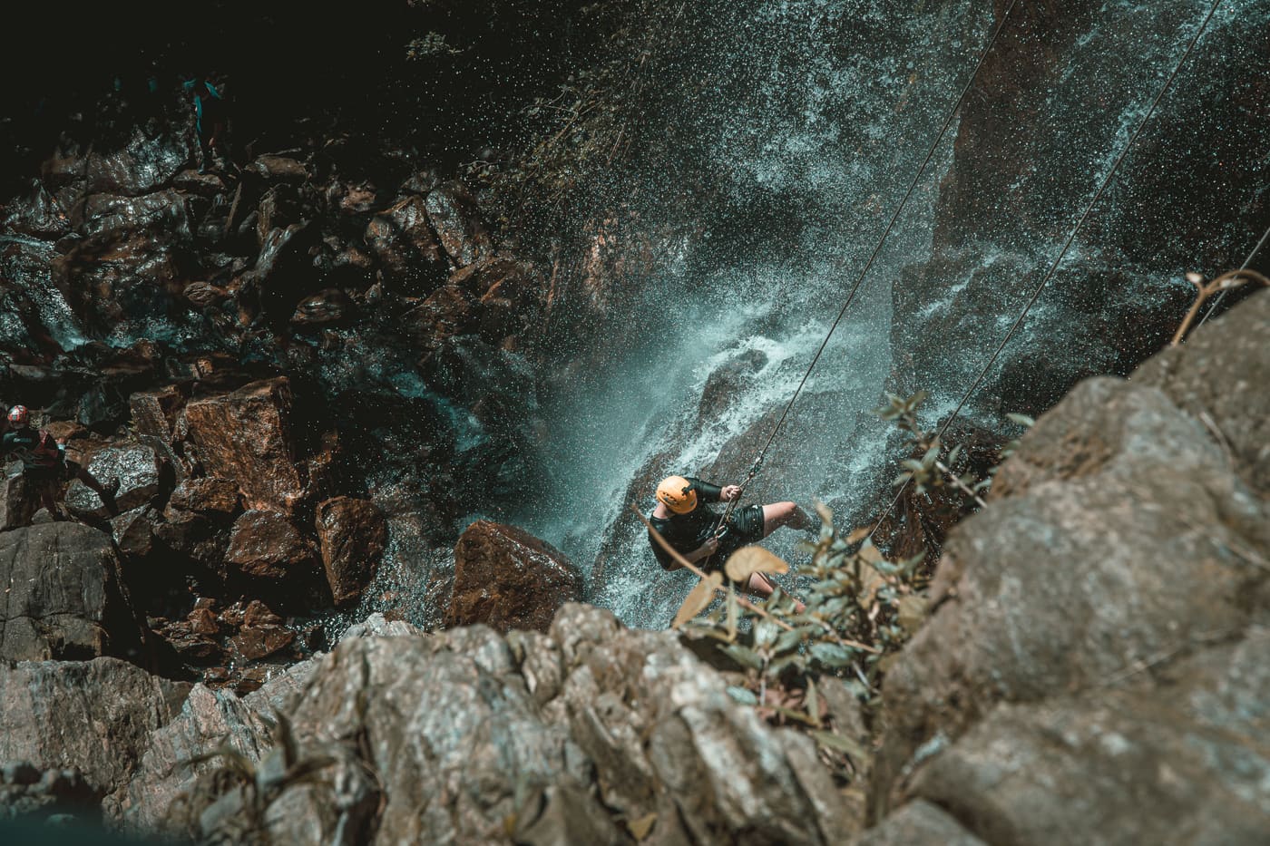 Persona en rápel descendiendo una cascada en un barranco encajonado