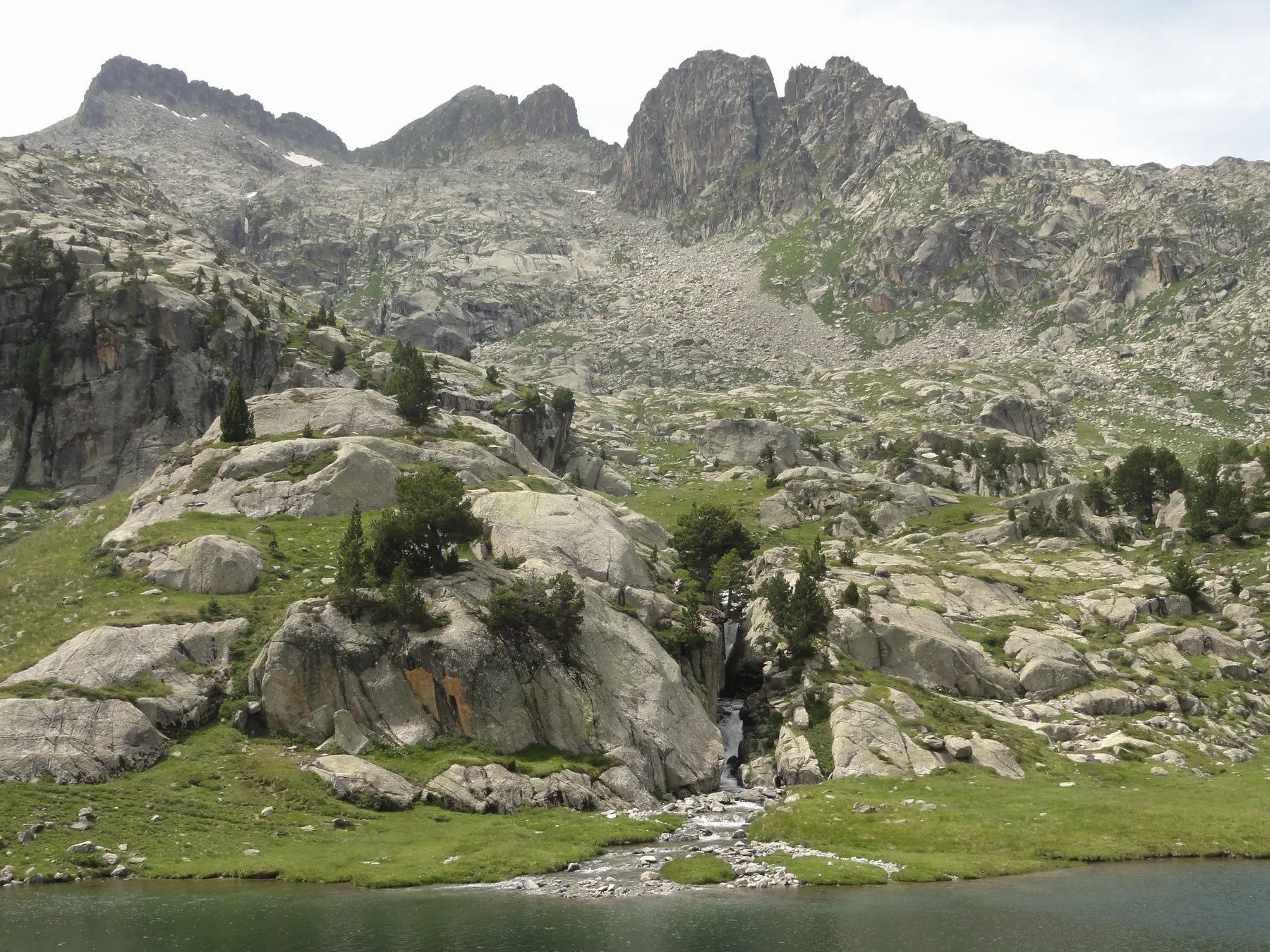Losas de granito y un reguero cayendo al lago en la parte alta del circo de Colomers, con el Pic de la Tallada Llarga al fondo