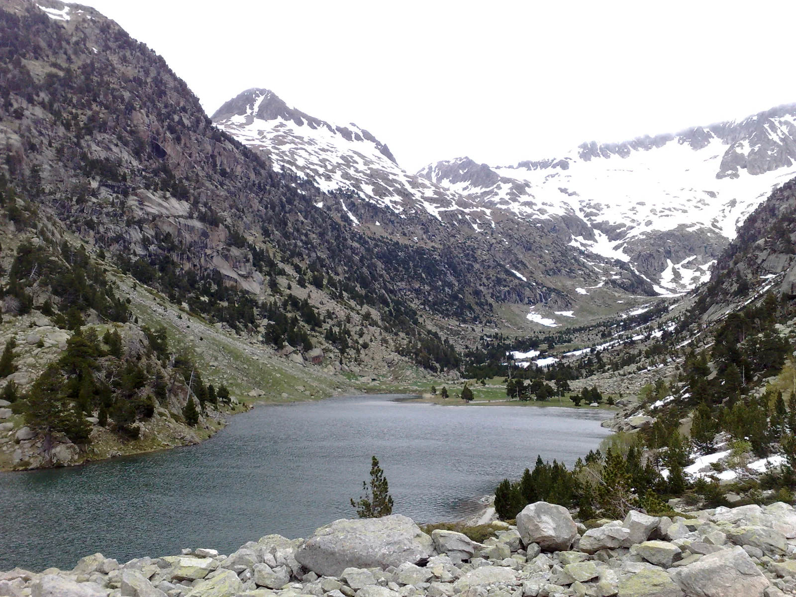 Estany de Besiberri, lago alpino bajo picos con nieve en el Pirineo de la Alta Ribagorça
