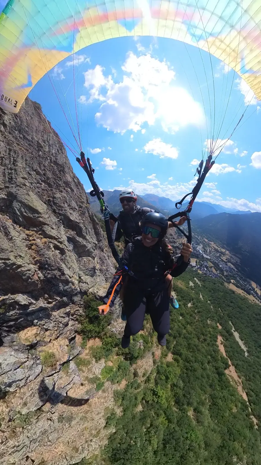 Piloto y pasajera en un vuelo biplaza junto a paredes rocosas de los Pirineos