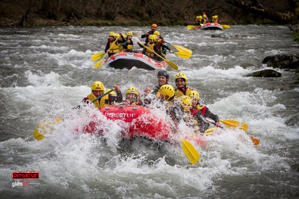 Grupo descendiendo aguas bravas del río Garona en balsa de rafting, con guía y equipo completo