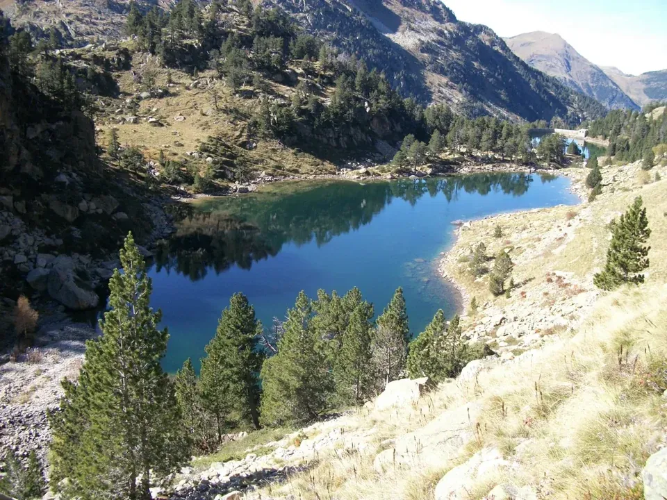 Lago de Montcasau de aguas azules rodeado de pinos y laderas