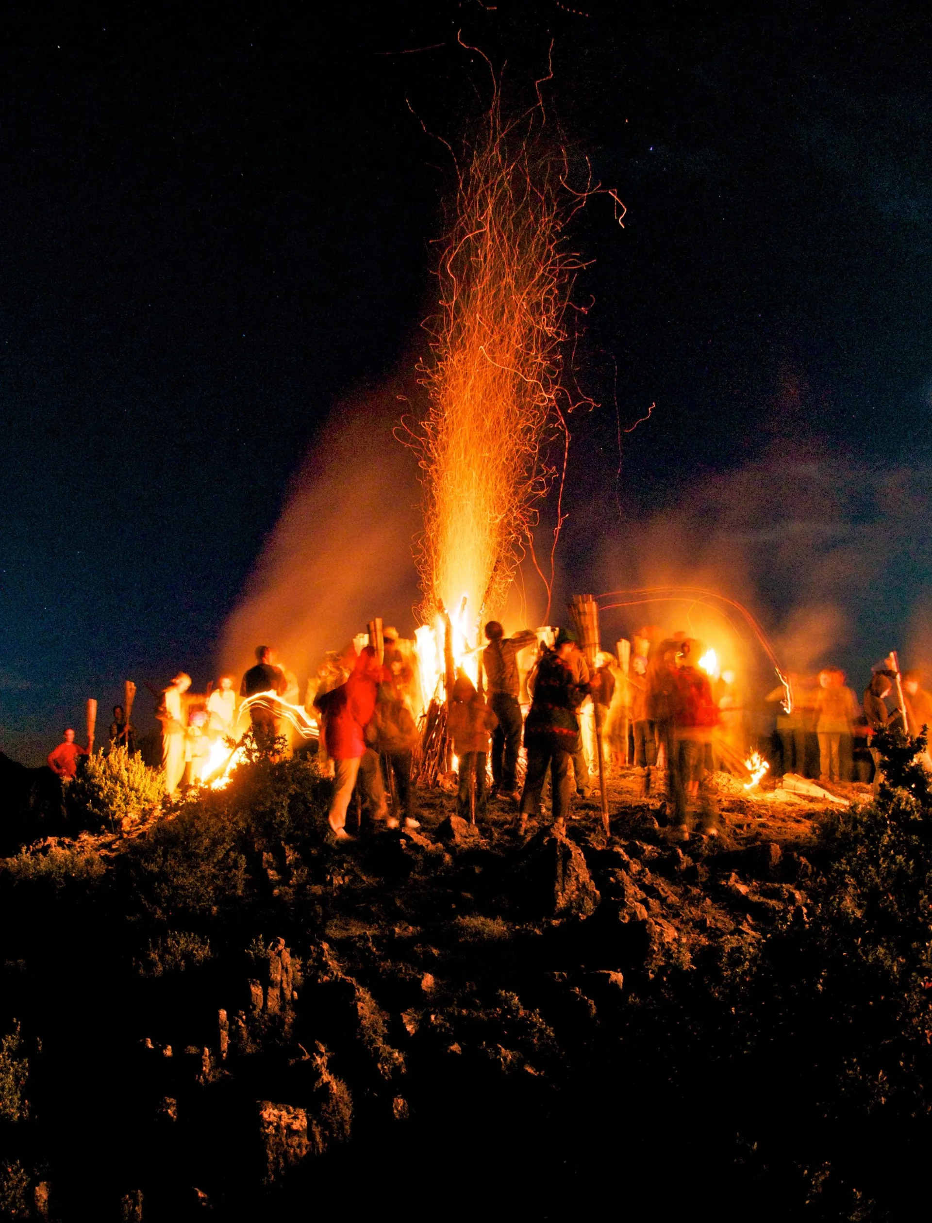 Hoguera tradicional de fuego con gente alrededor durante la noche en el Pirineo