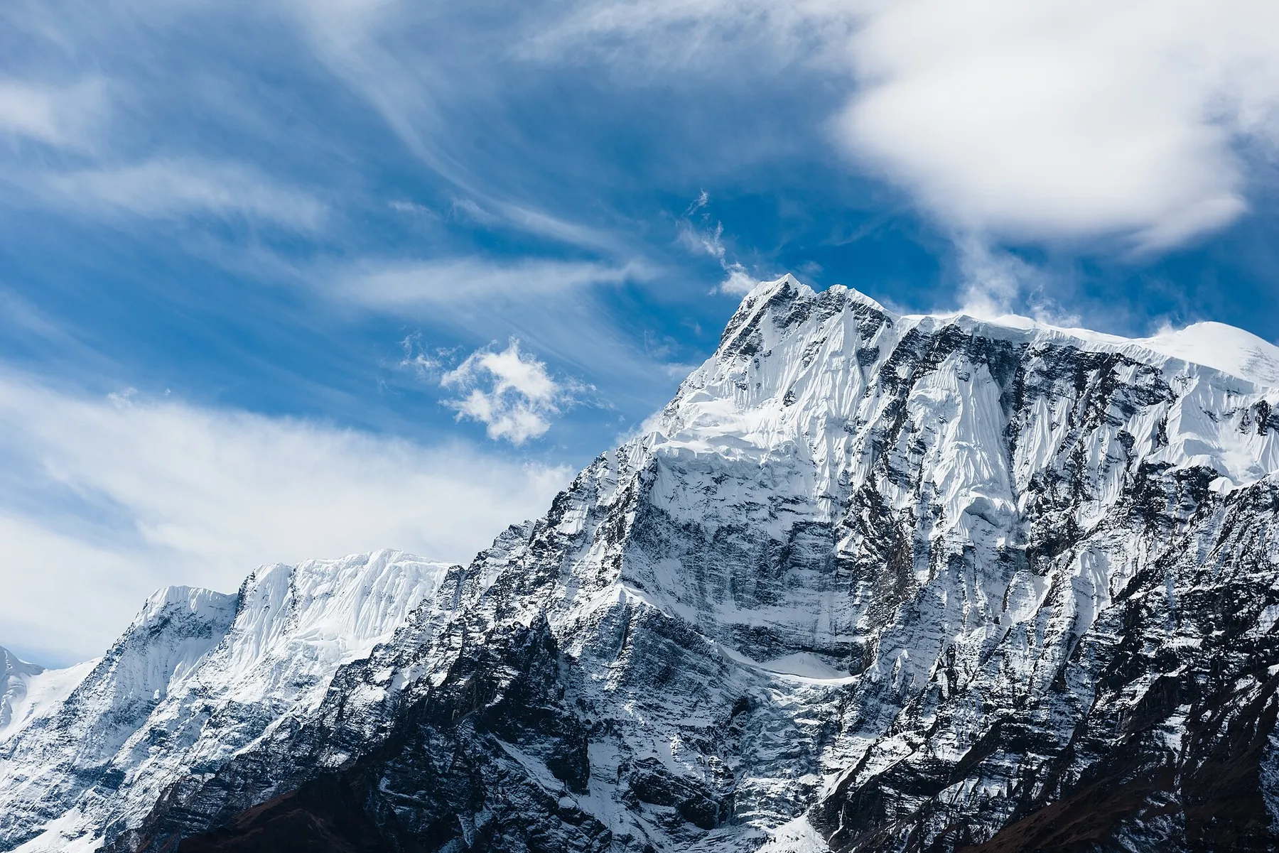 Picos nevados del Annapurna bajo un cielo azul con nubes, vistos desde el circuito del Annapurna