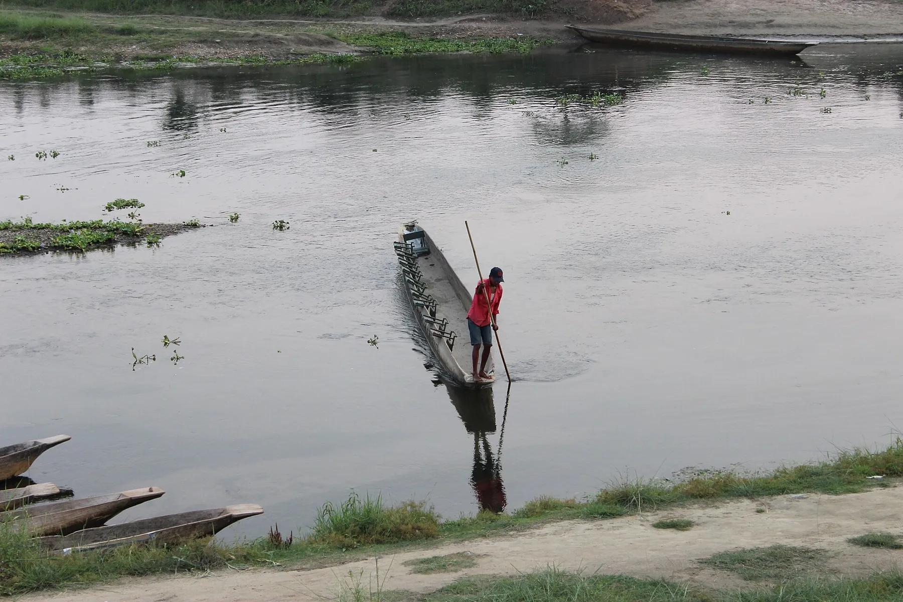 Un barquero avanza con una pértiga en una canoa de madera por el río Rapti, en el Terai nepalí