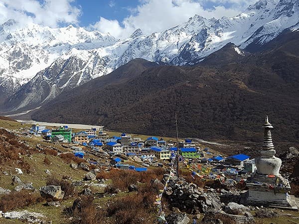 Vista aérea de Kyanjin Gompa, aldea de tejados azules con una estupa y picos nevados del Langtang al fondo