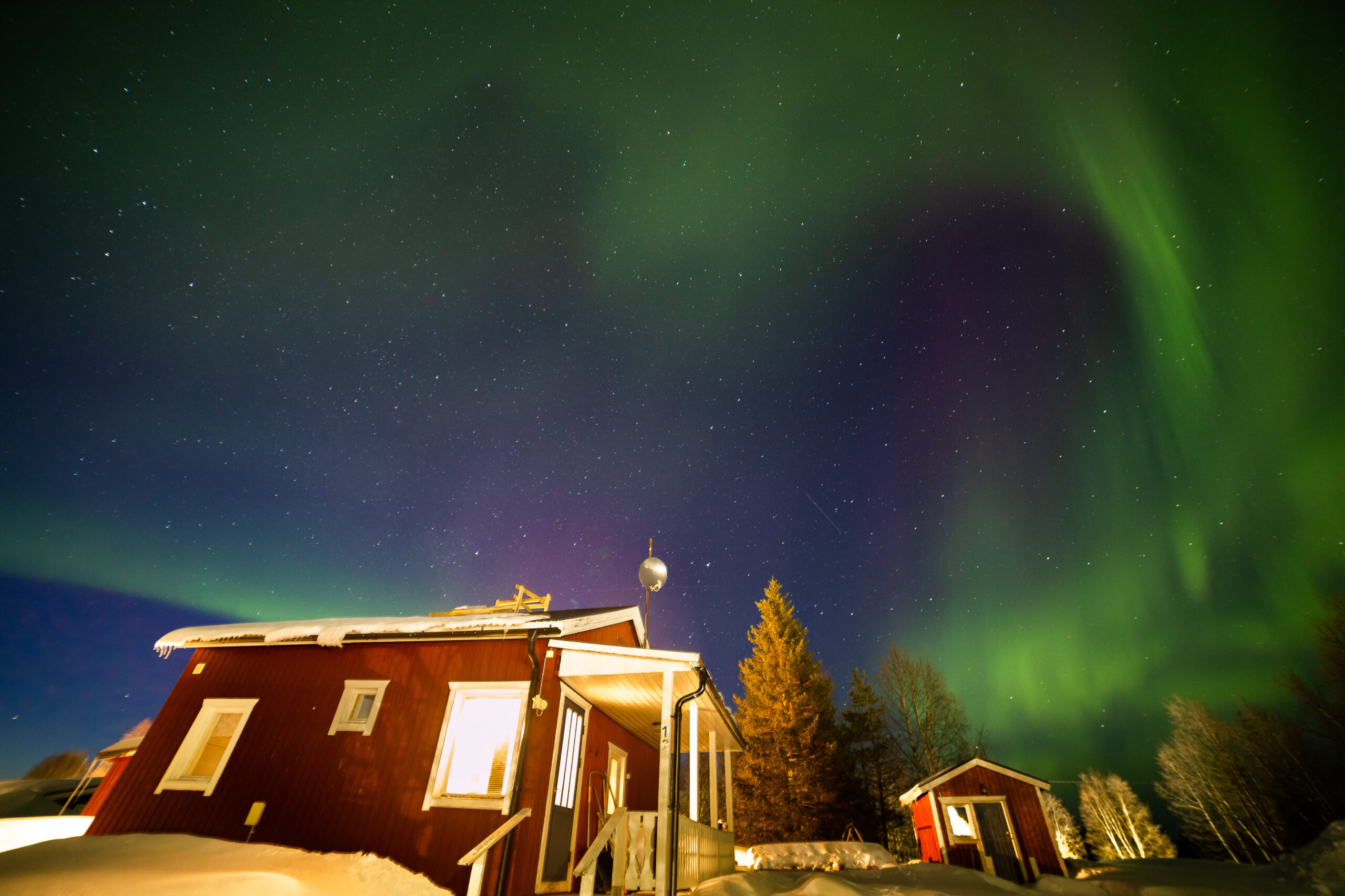 Aurora boreal verde sobre una cabaña roja tradicional sueca en la Laponia ártica