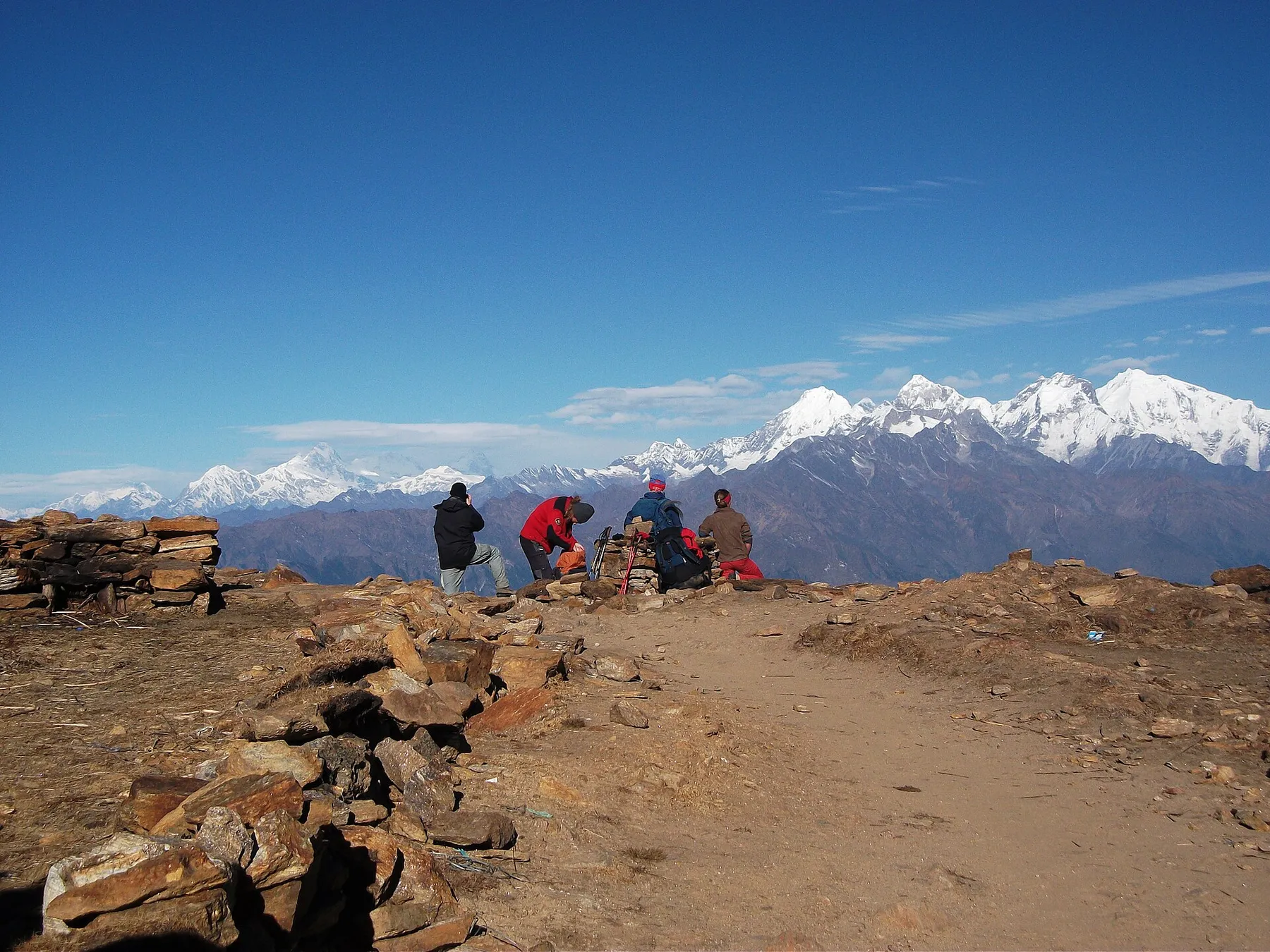 Viajeros descansando en un collado con la cordillera nevada del Ganesh Himal al fondo